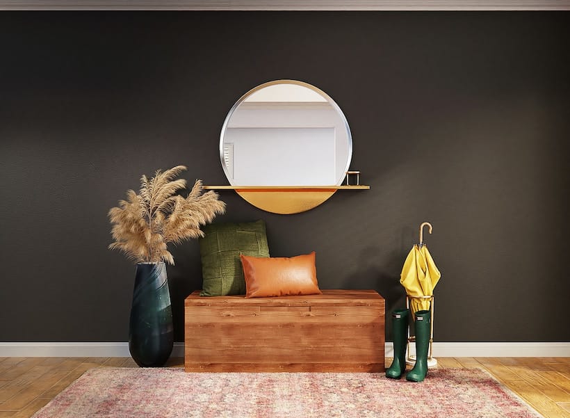 An entryway with a round mirror and a wooden bench.